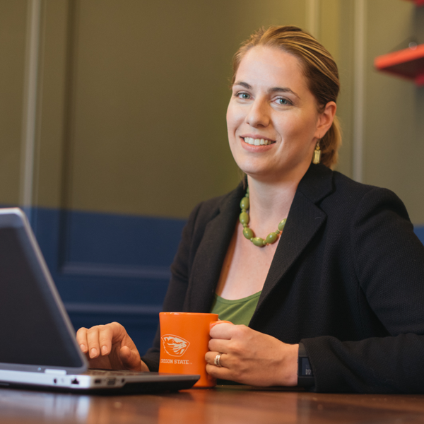 A person working on their laptop with an OSU coffee cup